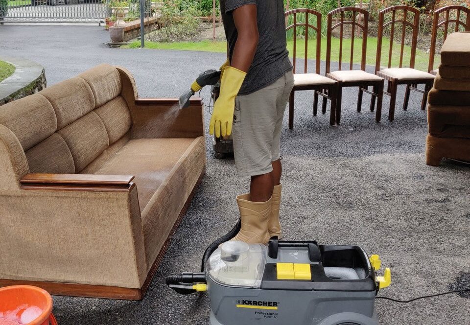 Man vacuuming couch for sofa cleaning services in Dubai